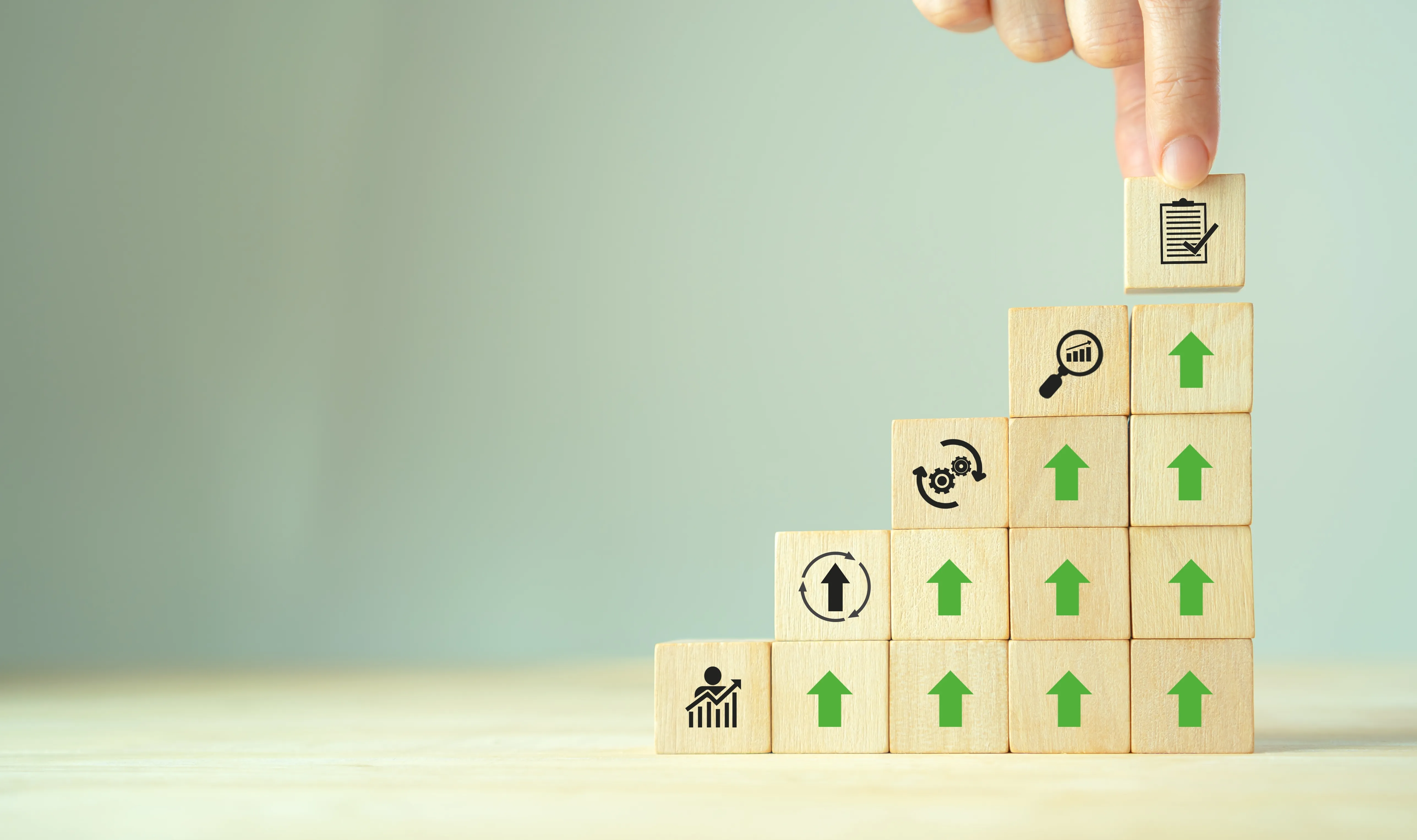 Stacked wooden blocks with upward arrows and skill icons representing a step-by-step upskilling progression